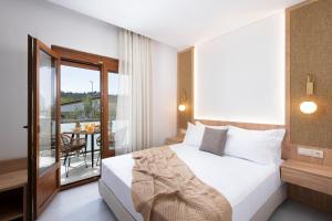 a bedroom with a bed and a balcony with a table at Opalium Beach Front Suites in Potos