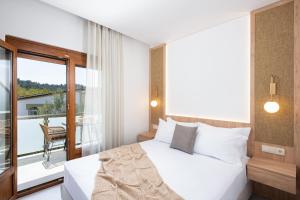 a bedroom with a white bed and a balcony at Opalium Beach Front Suites in Potos