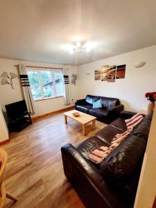 a living room with a leather couch and a table at Cosy lodge 82 Hengar Manor in Michaelstow
