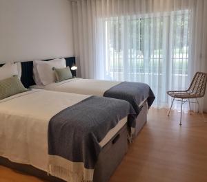 two beds in a bedroom with a chair and a window at Barra B Suite Apartment - 4min walk from BEACH, Terrace in Praia da Barra