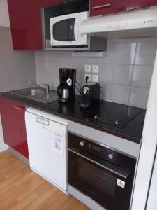 a kitchen with a sink and a stove and a microwave at Appartement Reines des Pyrénées, T2, entier, centre Luchon, tarif cure thermale, wifi, casier à skis, ascenseur in Luchon +3 photos