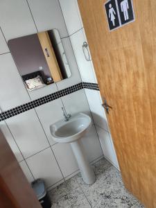 a bathroom with a white sink and a wooden door at Soninho Bão in Cunha
