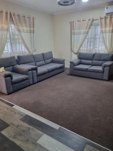 two blue couches in a living room with windows at 2 bedroom house in Tema in Tema