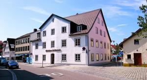 a white and pink building on a city street at Gästehaus Stiftsstadt - urban lifestyle Kempten by Hotel Peterhof in Kempten