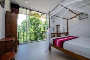 a bedroom with a canopy bed and a balcony at d villa galle in Galle