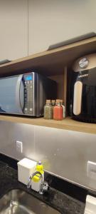 eine Mikrowelle auf einem Regal über einer Küchenspüle in der Unterkunft Flat Makia Beach Muro Alto, Porto de Galinhas in Ipojuca