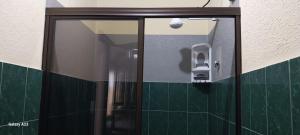 a mirror in a bathroom with green tiles at Apartamentos equipados lc2 in Canoas +16 photos