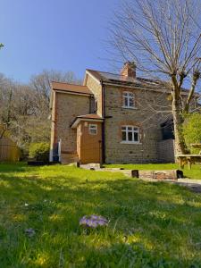 an old brick house in a field of grass at Willow Cottage in Longney
