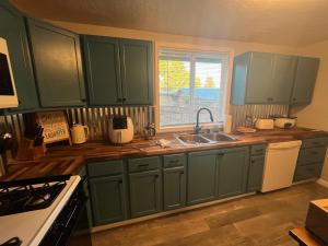 a kitchen with green cabinets and a sink and a window at Blue Mountain Retreat in Elgin