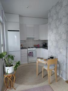 a kitchen with white cabinets and a table and a chair at Annela, kodikas kaksio Euran sydämessä in Eura