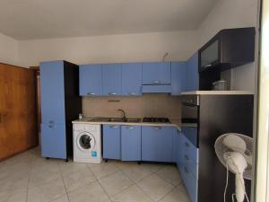 a kitchen with blue cabinets and a washing machine at casavacanza la vite in Alezio