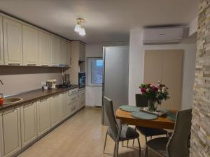 a kitchen with a table and chairs and a kitchen with a refrigerator at Victory Apartament in Ocna-Mureşului