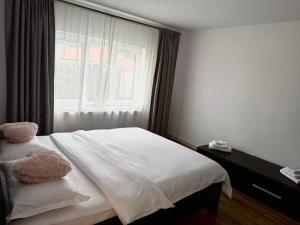 Un dormitorio con una cama blanca con una ventana. en Victory Apartament, en Ocna-Mureşului