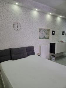 ein Schlafzimmer mit einem weißen Bett und einer Uhr an der Wand in der Unterkunft Vieste Holiday Homes - Appartamento Vacanze Centro Luxury con balcone a pochi passi dal mare in Vieste