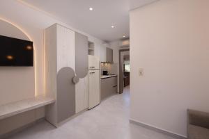 a kitchen with white walls and a tv on a wall at Opalium Beach Front Suites in Potos