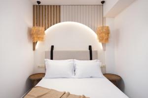 a bedroom with a bed with white sheets and pillows at Opalium Beach Front Suites in Potos