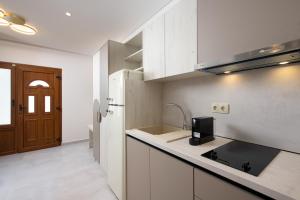 a kitchen with white cabinets and a sink at Opalium Beach Front Suites in Potos
