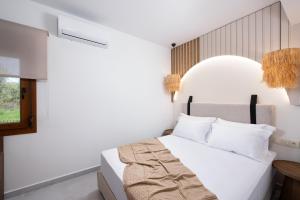 a white bedroom with a bed and a window at Opalium Beach Front Suites in Potos