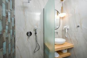 a bathroom with a shower with a sink and a mirror at Opalium Beach Front Suites in Potos