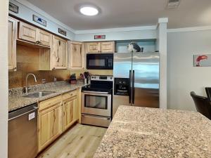 a kitchen with wooden cabinets and stainless steel appliances at Smiling Jacks Escape in Mustang Beach