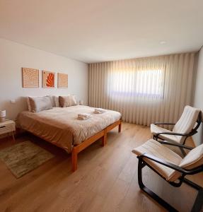 a bedroom with a large bed and a chair at Casa Couto Do Souto in Souto