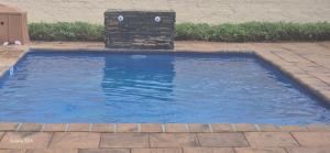 a small swimming pool with a stone fountain in a yard at AndriMat Roadside Guest Lodge in Mogwase