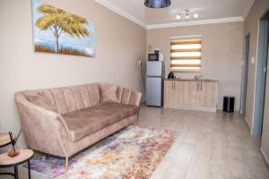 a living room with a couch and a kitchen at AndriMat Roadside Guest Lodge in Mogwase