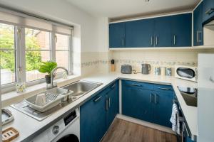 a kitchen with blue cabinets and a sink and a window at Loughton Hideaway: Cozy 1BD Near Tube & Nature in Theydon Bois +17 photos