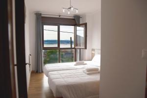 Dos camas en una habitación con una gran ventana. en Apartamentos Terramar, en Boiro