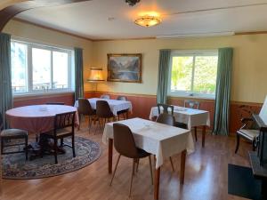 a dining room with tables and chairs and windows at Sognefjord Gjesteheim in Vangsnes