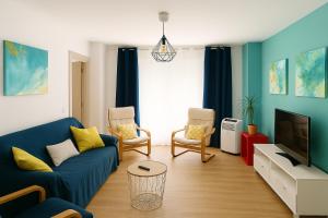 a living room with a blue couch and a tv at Avenida del Mar 14 Junio in Castellón de la Plana