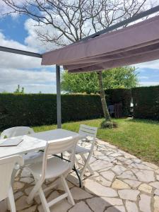 a white table and chairs under an umbrella at Maison dans résidence avec piscine in Saint-Palais-sur-Mer