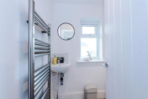 a white bathroom with a sink and a mirror at Stylish 3 Bedroom Home with Driveway, Family and Business Friendly in Mold +67 photos