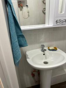 ein Badezimmer mit einem weißen Waschbecken und einem blauen Handtuch in der Unterkunft Promenade Burabay 2 in Borovoye