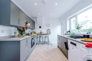 a kitchen with white cabinets and a large window at Stylish 3 Bedroom Home with Driveway, Family and Business Friendly in Mold