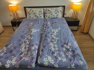Bett mit blauer Decke und 2 Lampen in der Unterkunft Апартаменти Арт in Stara Sagora