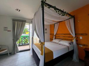 吉拉尔多特PH BOUTIQUE HOTEL Girardot的一间卧室设有一张天蓬床和一个阳台