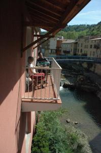 two people sitting on a balcony looking at a river at La résidence des bains forts in Rennes-les-Bains
