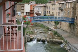a blue bridge over a river with waterfalls at La résidence des bains forts in Rennes-les-Bains