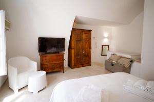a white bedroom with a bed and a television at Voltebianche in Martina Franca