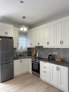 a kitchen with white cabinets and a stainless steel refrigerator at Poseidon Garden View Apartment in Perivólion