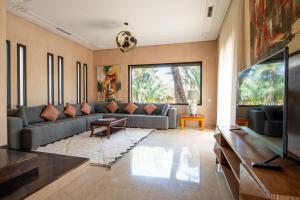 een woonkamer met een bank en een televisie bij Villa les Palmiers in Marrakesh