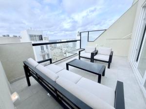 a balcony with white couches and chairs on a building at The Bugibba Central Penthouse! in St Paul's Bay +1 photo