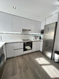 a kitchen with white cabinets and a stainless steel refrigerator at Cullera Sea and Mountain Balcony in Cullera +18 photos