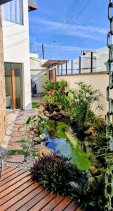 un cortile con uno stagno su un ponte di legno di Casa de Praia no Capricórnio I em Caraguatatuba SP a Caraguatatuba