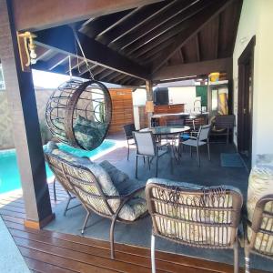 una terrazza con sedie e tavolo e una sala da pranzo di Casa de Praia no Capricórnio I em Caraguatatuba SP a Caraguatatuba