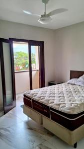 un letto in una camera da letto con una grande finestra di Casa de Praia no Capricórnio I em Caraguatatuba SP a Caraguatatuba Altre 37 foto