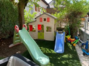 a playground with two slides and a play house at Maison du Bonheur, gîte Les Tilleuls in Le Pin