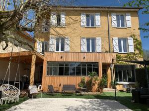 a building with windows and chairs in front of it at Maison du Bonheur, gîte Les Tilleuls in Le Pin