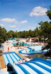 a large swimming pool with people at a resort at mh44 au calme 6 personnes Bois Dormant 4 étoiles in Saint-Jean-de-Monts